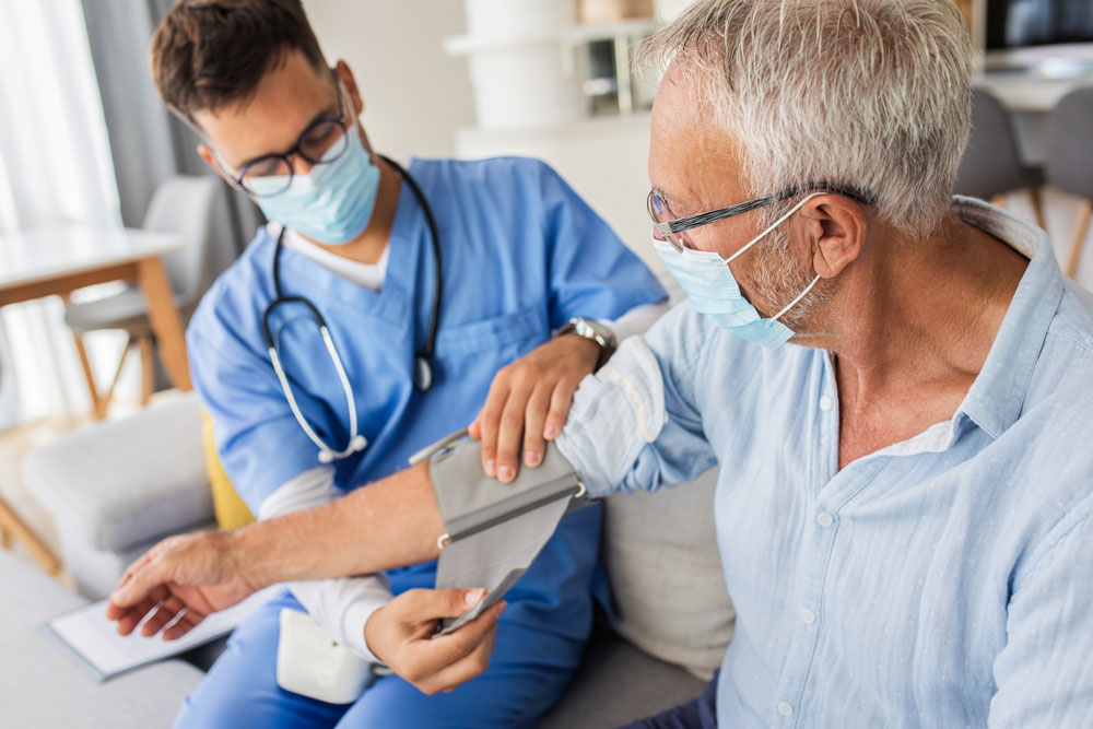 doctor in mask takes blood pressure of man wearing mask