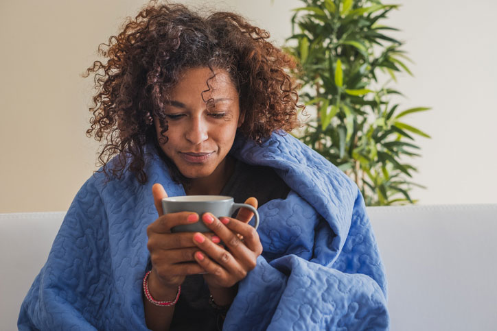 woman wrapped in blanket with cup of tea