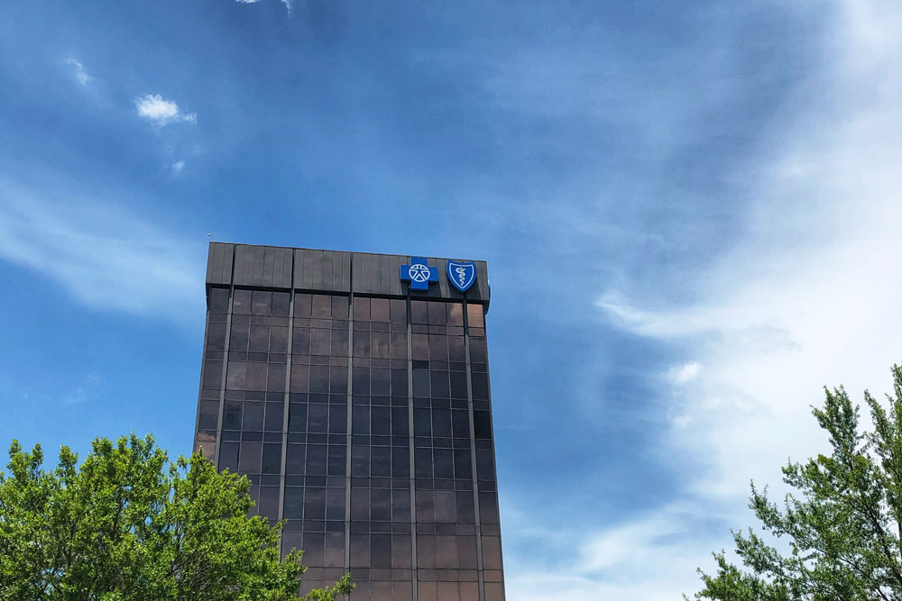 tall building with blue cross logo and blue sky