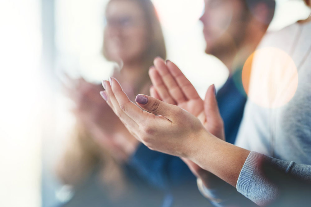 close up of hands clapping with people in the background