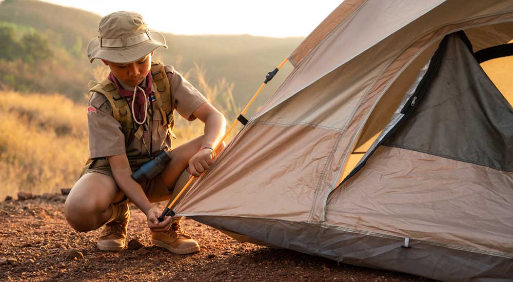 Young boy kneeling next to tent
