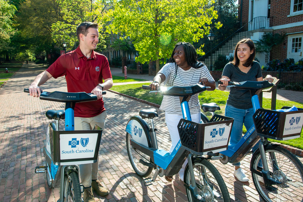 Man and two women walk outside with Blue Bikes