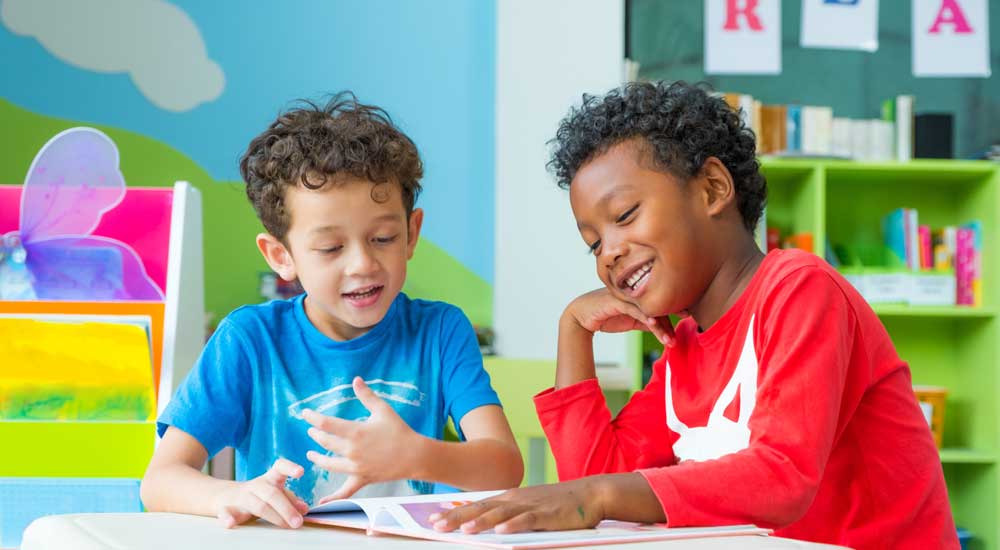 two little boys in colorful classroom looking at books