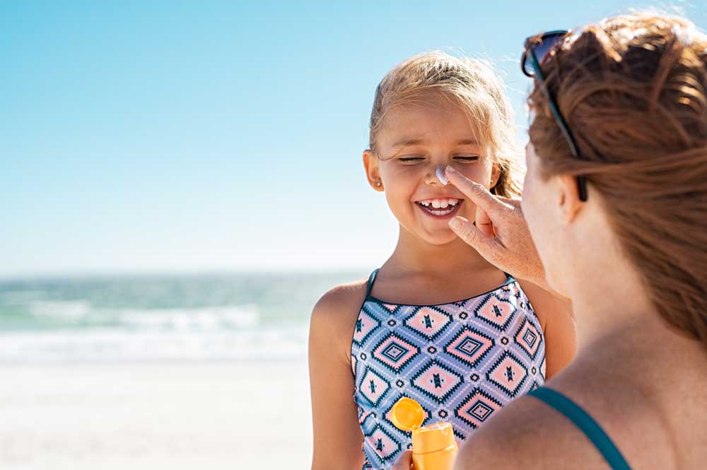 woman applying sunscreen to little girl's nose