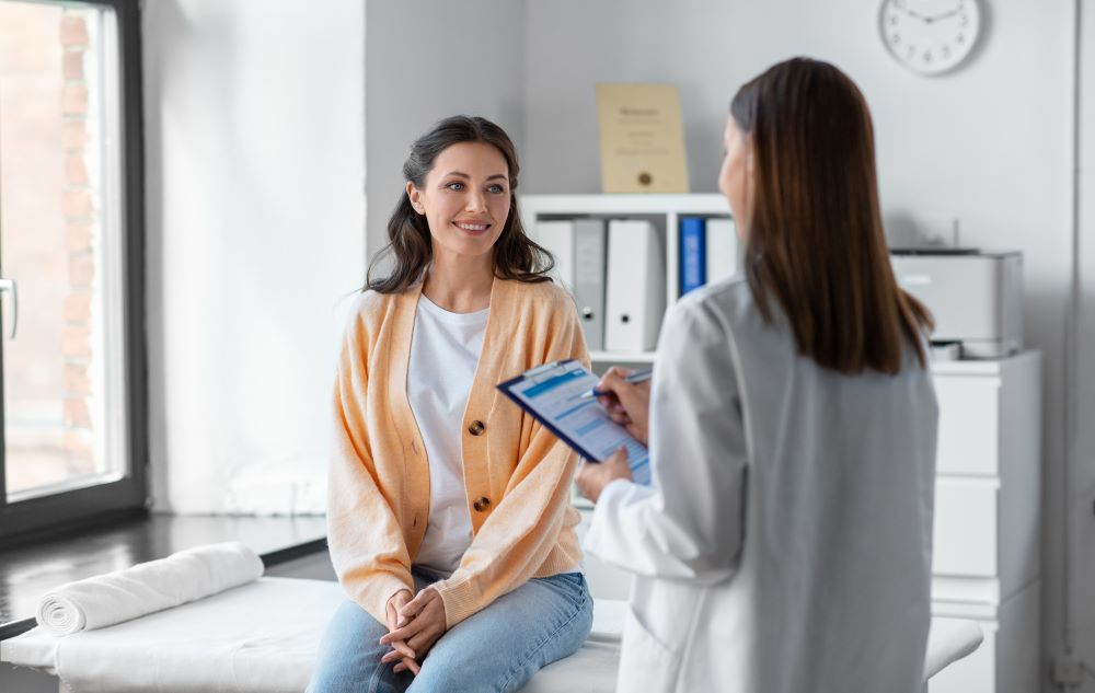 woman sitting on medical table smiling at doctor in white coat