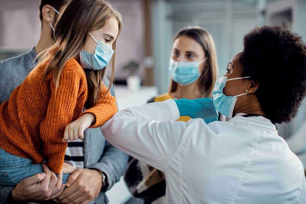 little girl with mask bumps elbow doctor in mask
