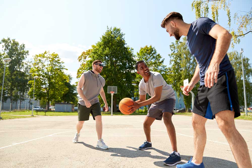 three men playing basketball outside