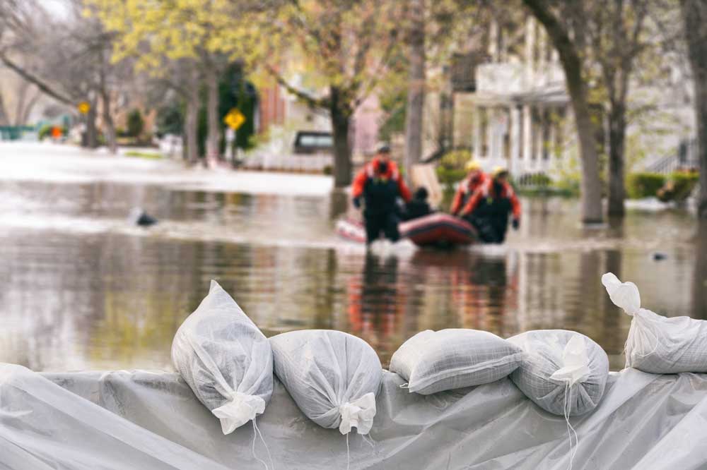 sandbags in foreground with rescue workers in flood