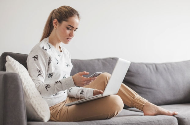 woman holds cell phone and laptop