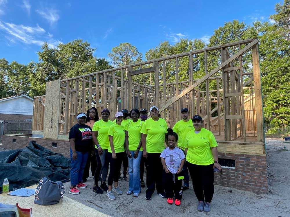 group of people standing in front of home being built